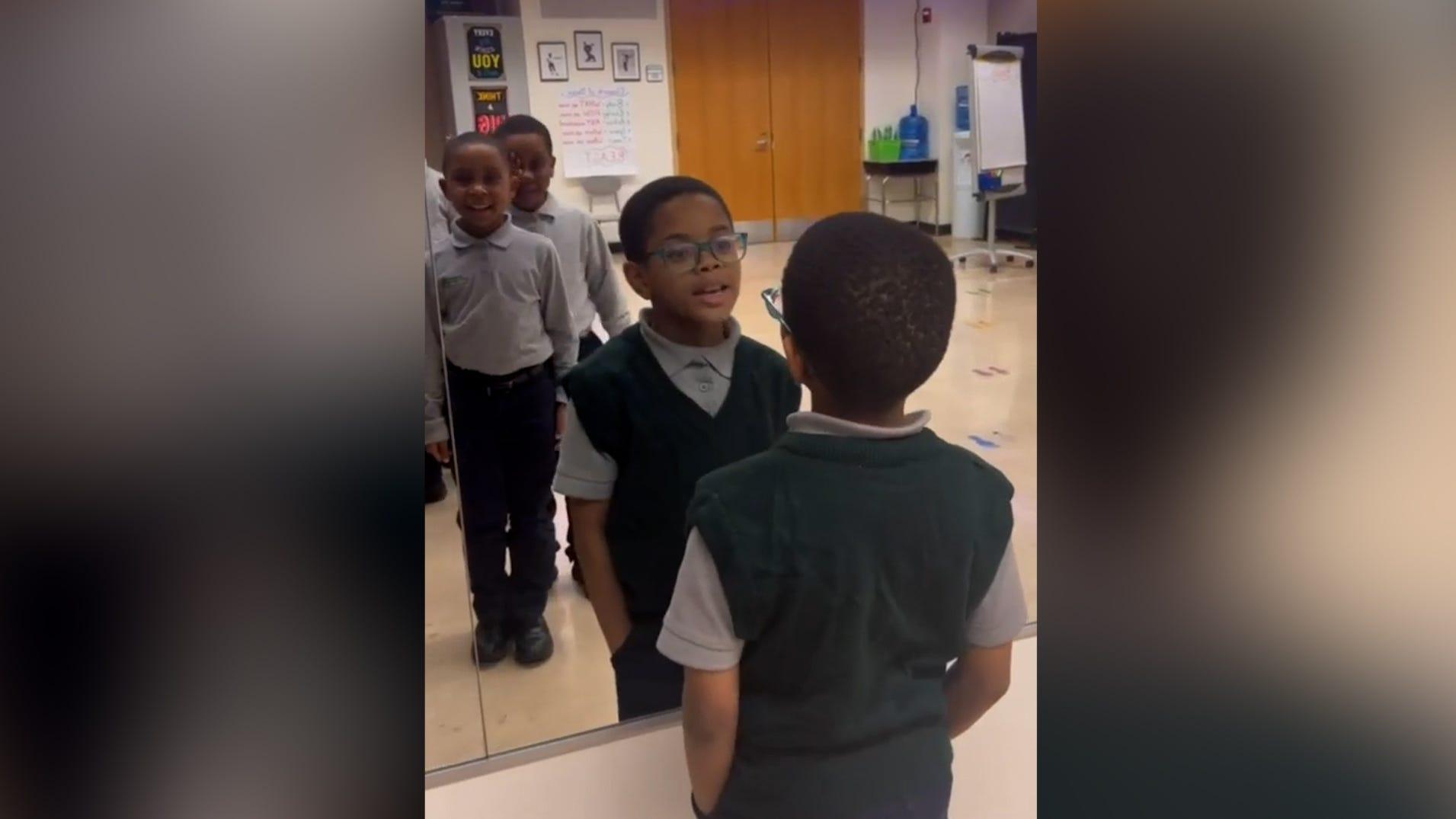 A group of young boys are lined up in front of a mirror.