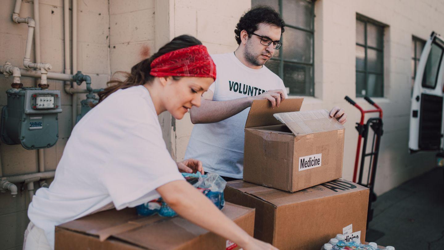 Two people at a table filled with supplies, wearing volunteer shirts