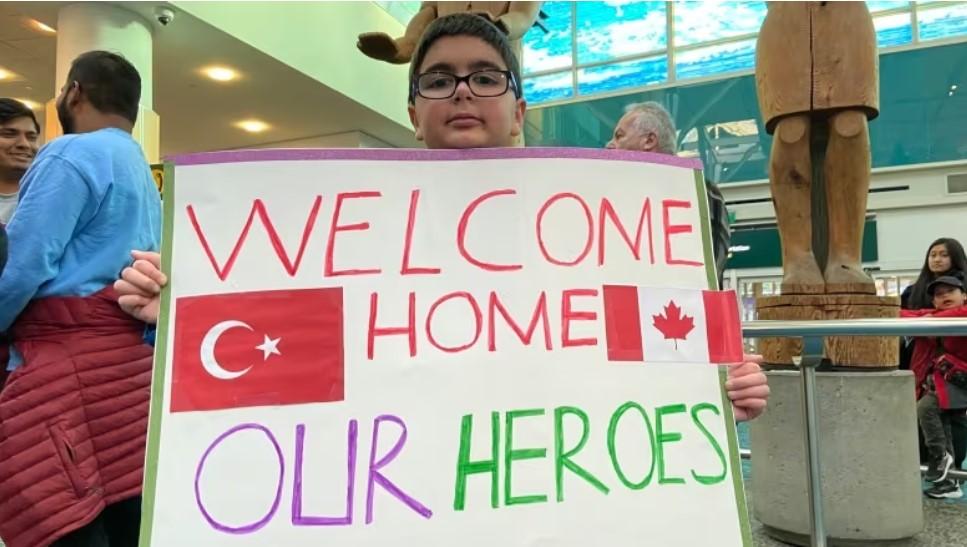 boy holding handmade sign at airport welcoming home our heroes
